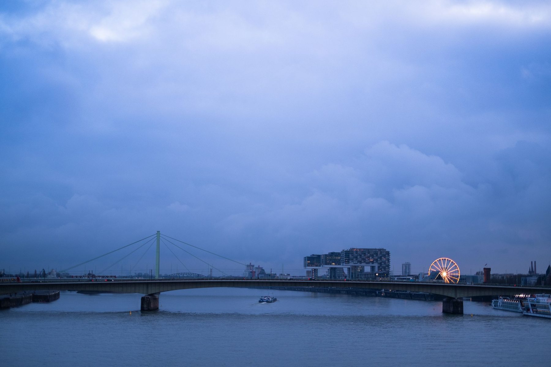 Change Management Beratung Köln bei CEx: Die Hohenzollernbrücke und das Riesenrad am Kölner Rheinufer in der Dämmerung